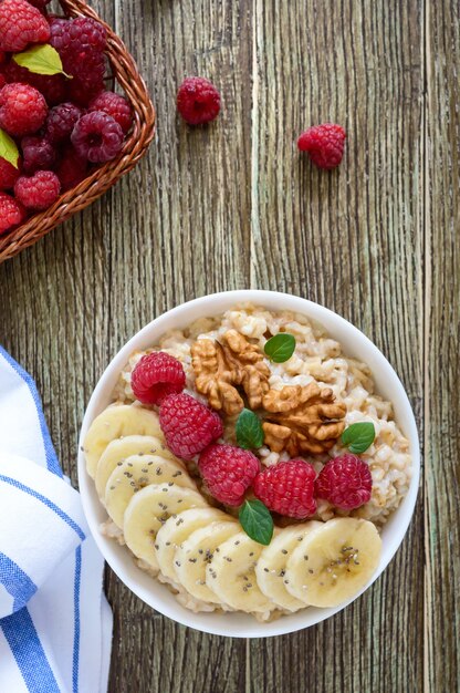 Gruau délicieux et sain avec banane, framboises, noix. Petit-déjeuner sain. Nourriture de remise en forme. Nutrition adéquat. Mise à plat. Vue de dessus.