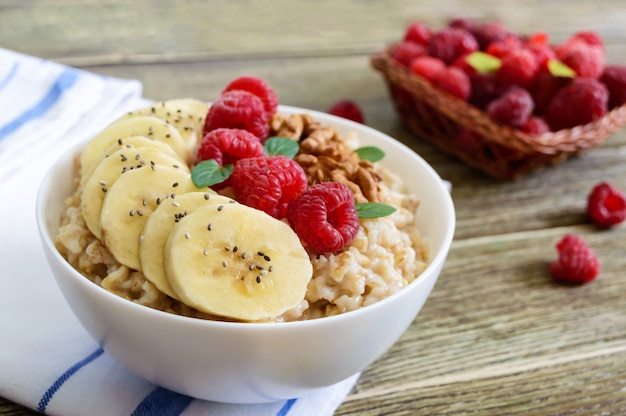 Gruau délicieux et sain avec banane, framboises, noix. Petit-déjeuner sain. Nourriture de remise en forme. Nutrition adéquat.