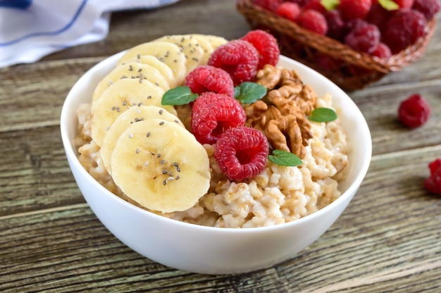 Gruau délicieux et sain avec banane, framboises, noix. Petit-déjeuner sain. Nourriture de remise en forme. Nutrition adéquat.