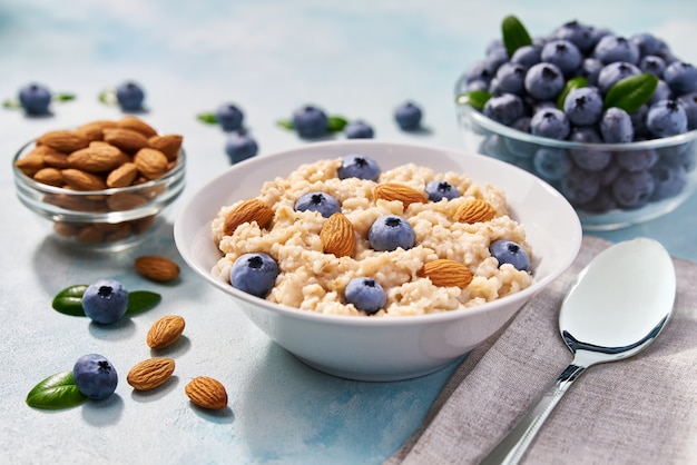 Gruau fait maison avec myrtilles fraîches et amandes pour le petit-déjeuner sur turquoise.