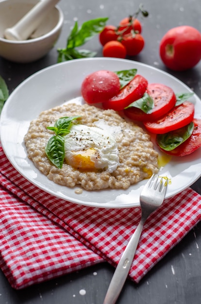 Gruau avec œuf poché, tomates et basilic. repas frais et savoureux de bonne nutrition.