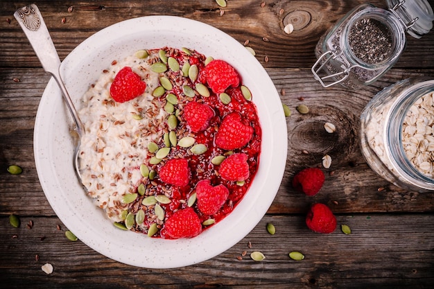 Gruau de petit déjeuner sain avec des framboises fraîches, des graines de lin et des graines de citrouille sur fond de bois