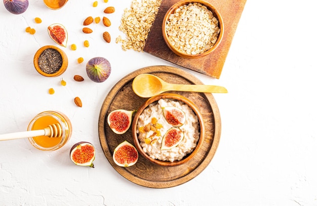 Gruau de petit-déjeuner sain et sain avec des fruits secs et des figues dans un bol sur une table blanche vue de dessus de nutrition équilibrée