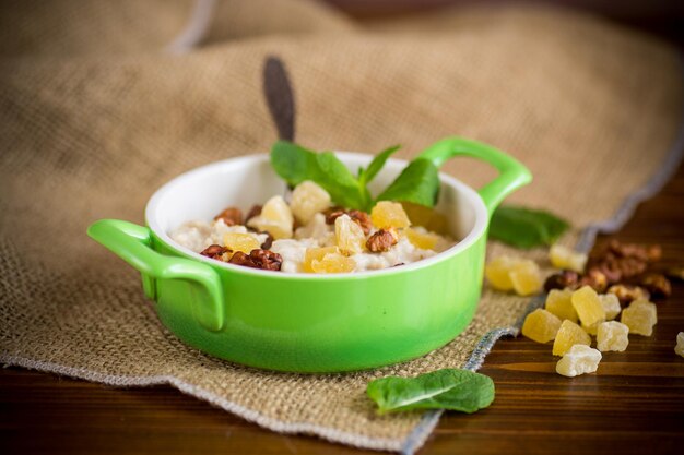 Gruau sucré bouilli cuit avec des noix et des fruits confits dans un bol sur une table en bois