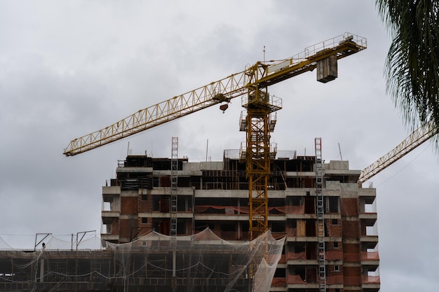 Une grue et un bâtiment en construction sur un fond de ciel nuageux