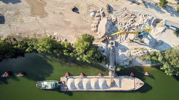 La grue charge du sable et du gravier sur une péniche pour le transport fluvial Drone aérien