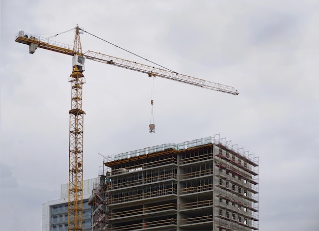 Grue de construction avec un bâtiment sur fond de ciel gris