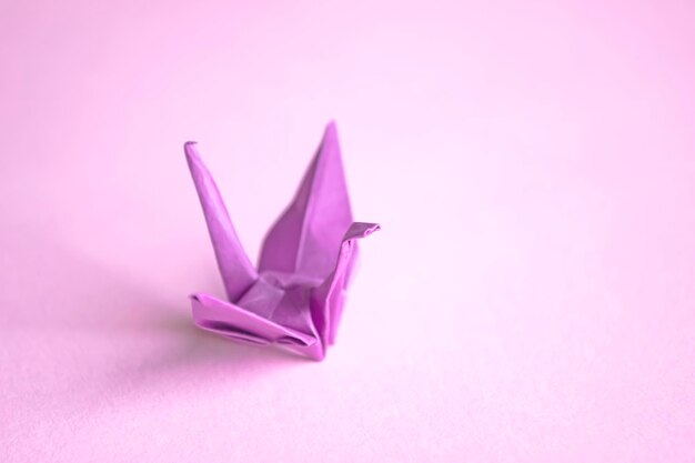 Grue en papier violet sur fond rose Origami La culture japonaise est une grue