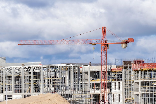 Grue à tour devant un bâtiment en construction sur fond de ciel clair