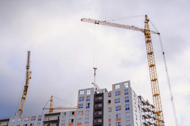 Grues et construction de bâtiments sur fond de ciel nuageux