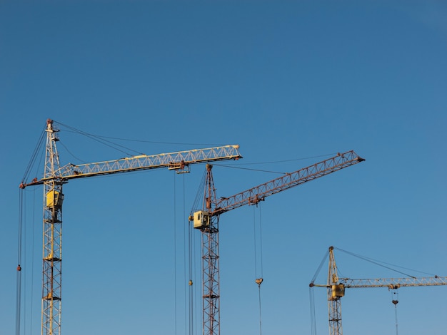 Grues de construction jaune sur fond de ciel nuageux