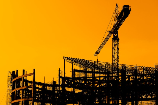 Grues de Derrick dans le chantier de construction au moment du coucher du soleil