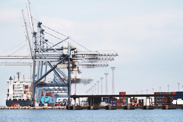 Grues à portique dans un port. Une photo d'un port avec des navires ancrés, des grues à portique et des conteneurs..