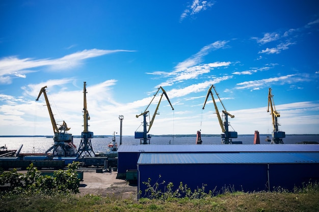 Grues portuaires contre le ciel bleu de la mer et les nuages blancs