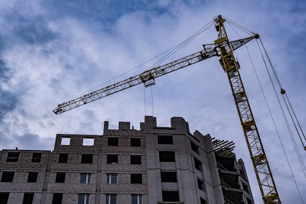 Grues à tour et immeubles de plusieurs étages inachevés en chantier le soir avec fond de nuage coloré spectaculaire