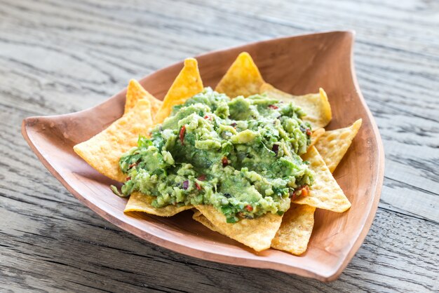 Guacamole aux croustilles de tortilla sur la surface en bois