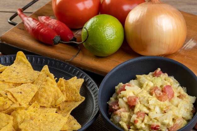 Guacamole aux tortillas avec des ingrédients en arrière-plan.