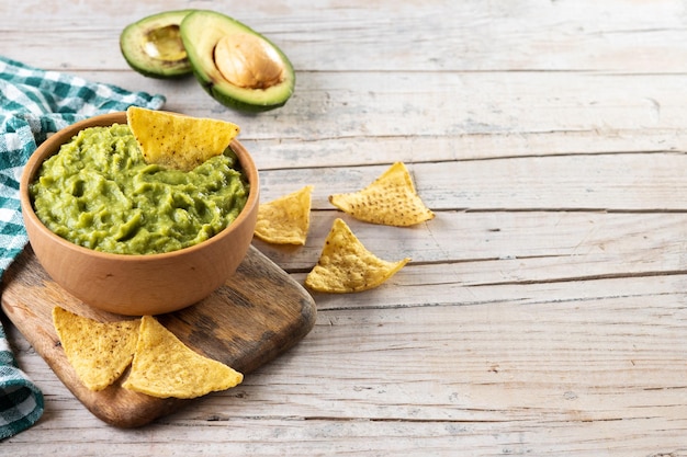 Guacamole mexicain avec chips de nacho dans un bol en bois