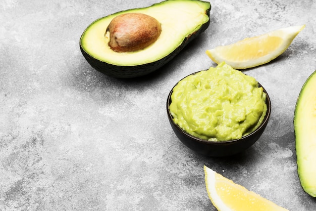 Guacamole de sauce latino-américaine traditionnelle dans un bol et avocats mûrs et citrons.