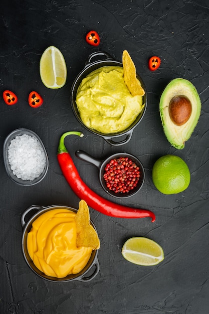 Guacamole vert et sauce trempette au fromage jaune pour tacos mexicains traditionnels, sur table noire, vue de dessus ou mise à plat