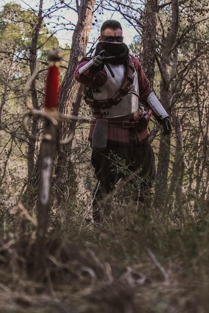 Photo guerrero medieval en el bosque, llevando una espada y una antorcha.