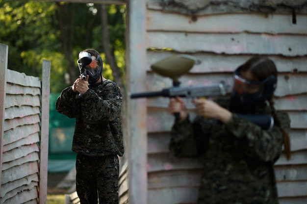 Le guerrier de paintball tire avec le pistolet de l'abri