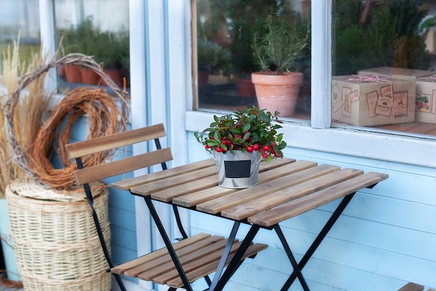 Gui de Noël avec berrys rouges en pot sur table en bois. maison sur terrasse maison