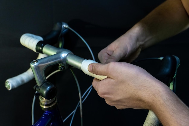 Guidon de vélo de route et levier de commande double sur fond noir Installer du ruban de guidon blanc Réparation de vélo dans un atelier moderne Gros plan de ruban isolant blanc