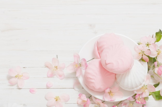 Guimauve rose et blanche avec des fleurs de pomme sur fond de bois