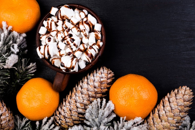 Guimauve sucrée de Noël avec du chocolat dans une tasse brune sur une surface noire à plat