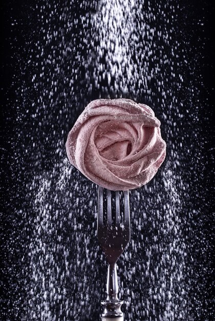 Guimauve sucrée rose faite maison sur une fourchette sur fond sombre