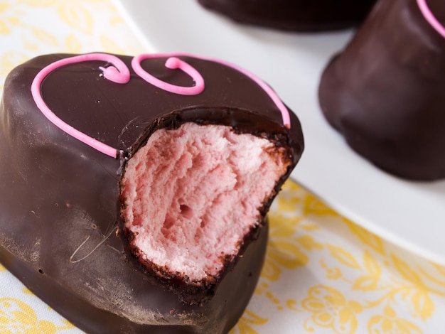 Guimauves aux fraises enrobées de chocolat gastronomique sur fond blanc.