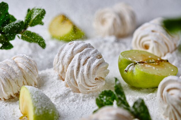 Guimauves aux pommes faites à la main sur fond de sucre glace. Dessert sous la neige. La douceur est agrémentée de pommes et de menthe.