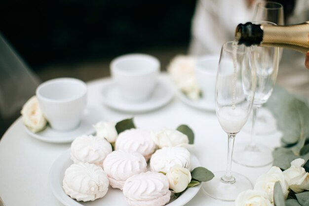 Guimauves blanches et roses et champagne sur la table de mariage. Dîner festif