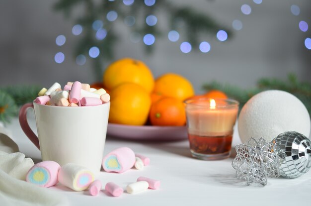 Guimauves, mandarines, bougies et boules de Noël sur fond de bokeh. Décoration de nouvel an.