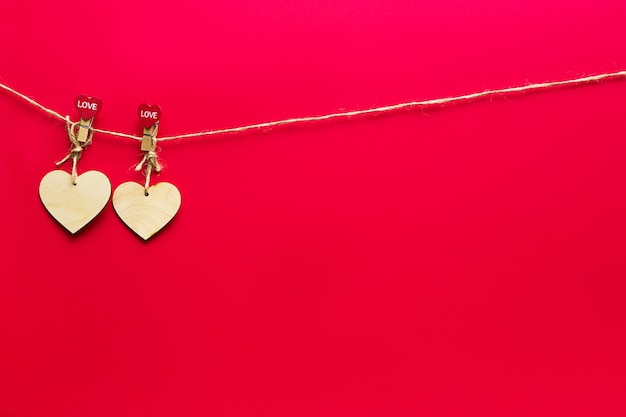 Guirlande de coeurs en bois avec des pinces à linge avec l'inscription LOVE sur fond rouge. Saint-Valentin, espace copie, lumières de Noël, flyer, amoureux