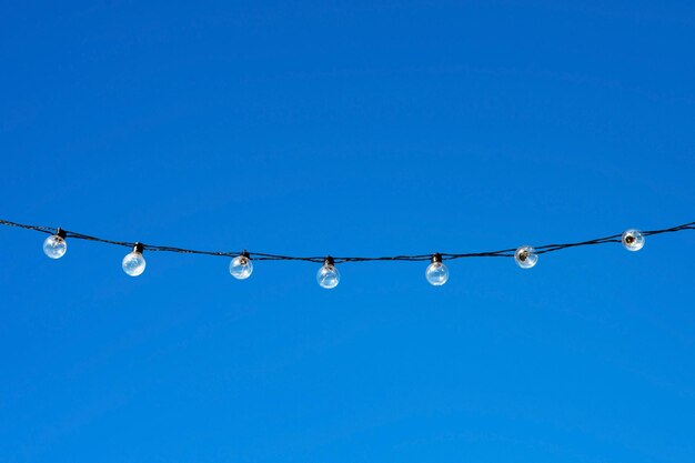 Guirlande de lampes sur fond de ciel bleu. Concept de célébration d'illumination