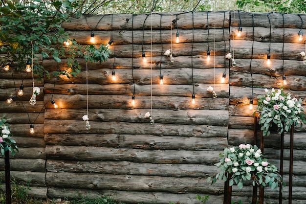 Guirlande murale en bois décorée d'ampoules lumineuses et de lampes électriques décorées de fleurs Décoration florale de mariage originale Zone de salon de réception de mariage