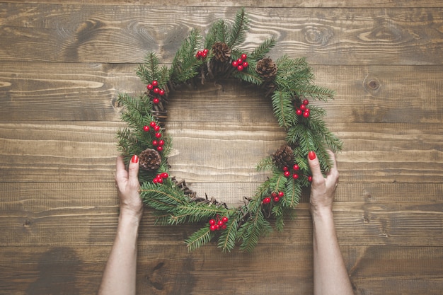 Guirlande de Noël de branches d'épinette avec baies de houx sur planche de bois.