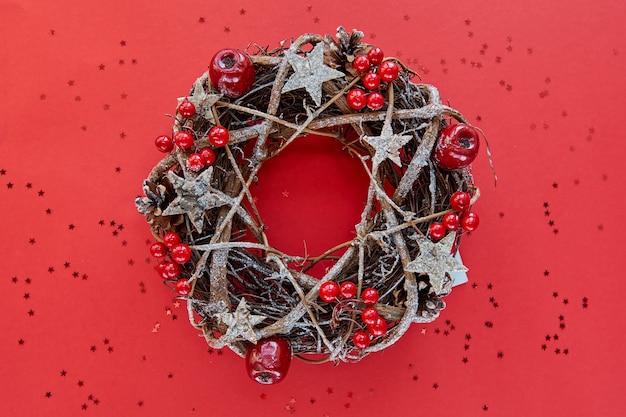 Guirlande de Noël faite de branches décorées d'étoiles en bois d'or et de bulles de fruits rouges isolés sur fond rouge