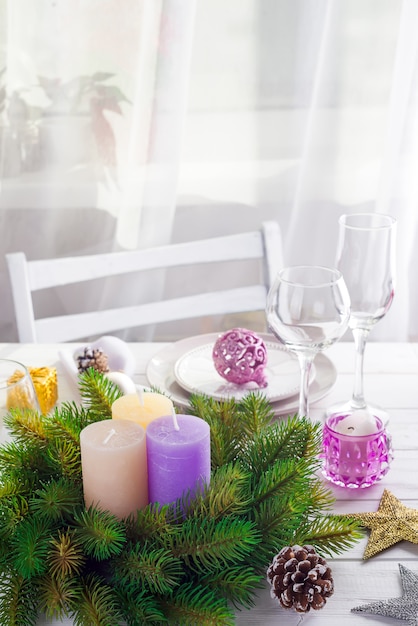Guirlande de Noël avec de grandes bougies colorées sur une table avec un réglage de table de Noël