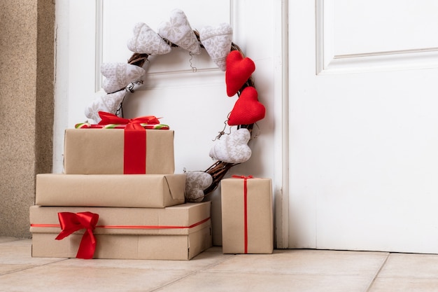 Guirlande de vacances avec des coeurs et des boîtes décorées de shopping sur le sol près de la porte blanche