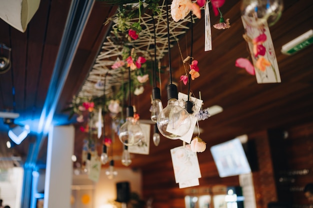 Guirlandes de lampes rétro sur le bar décorées de fleurs et de cartes postales