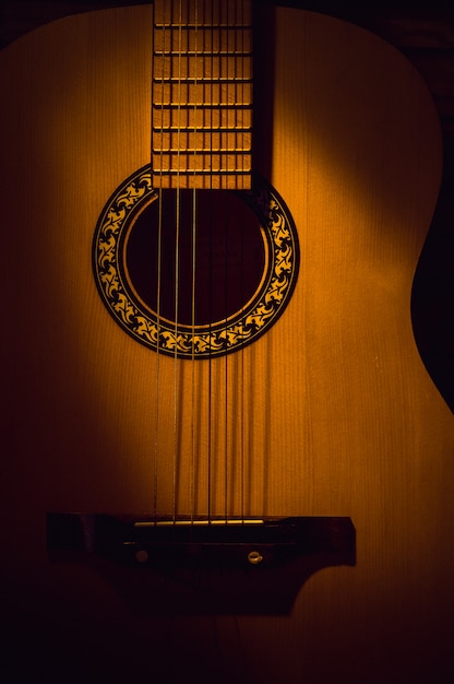 Guitare acoustique en gros plan dans l&#39;obscurité, éclairée par un faisceau de lumière.