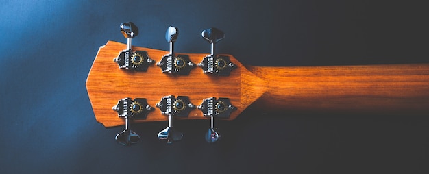 Guitare acoustique, instrument de musique reposant contre un mur noir foncé avec espace copie, gros plan d'une guitare classique en bois