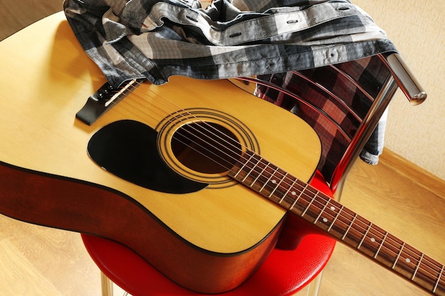 Guitare acoustique sur tabouret rouge dans le studio en gros plan