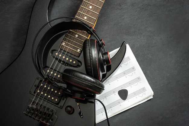 Photo guitare électrique noire et casque sur le sol.