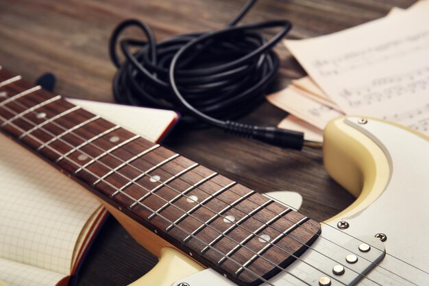 Guitare électrique avec notes de musique et cordon sur fond de bois