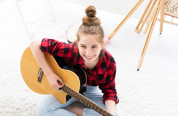 Photo guitariste de fille souriante avec instrument de musique regardant du sol