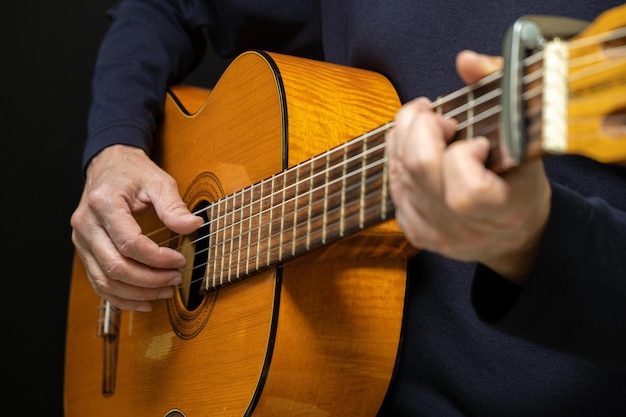 Photo guitariste jouant de la guitare acoustique sur fond noir mise au point sélective un homme jouant de la guitare acoustique